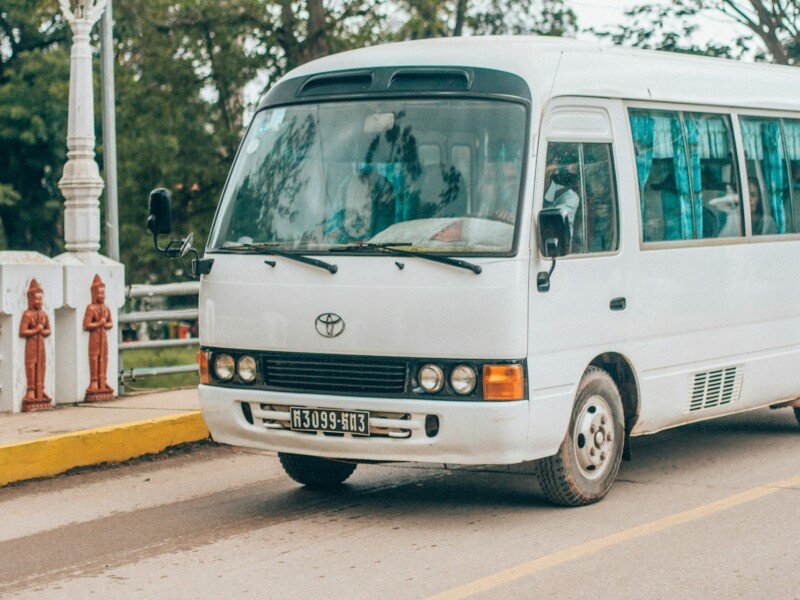 White minibus on a coastal road, the kind used for hotel transfers